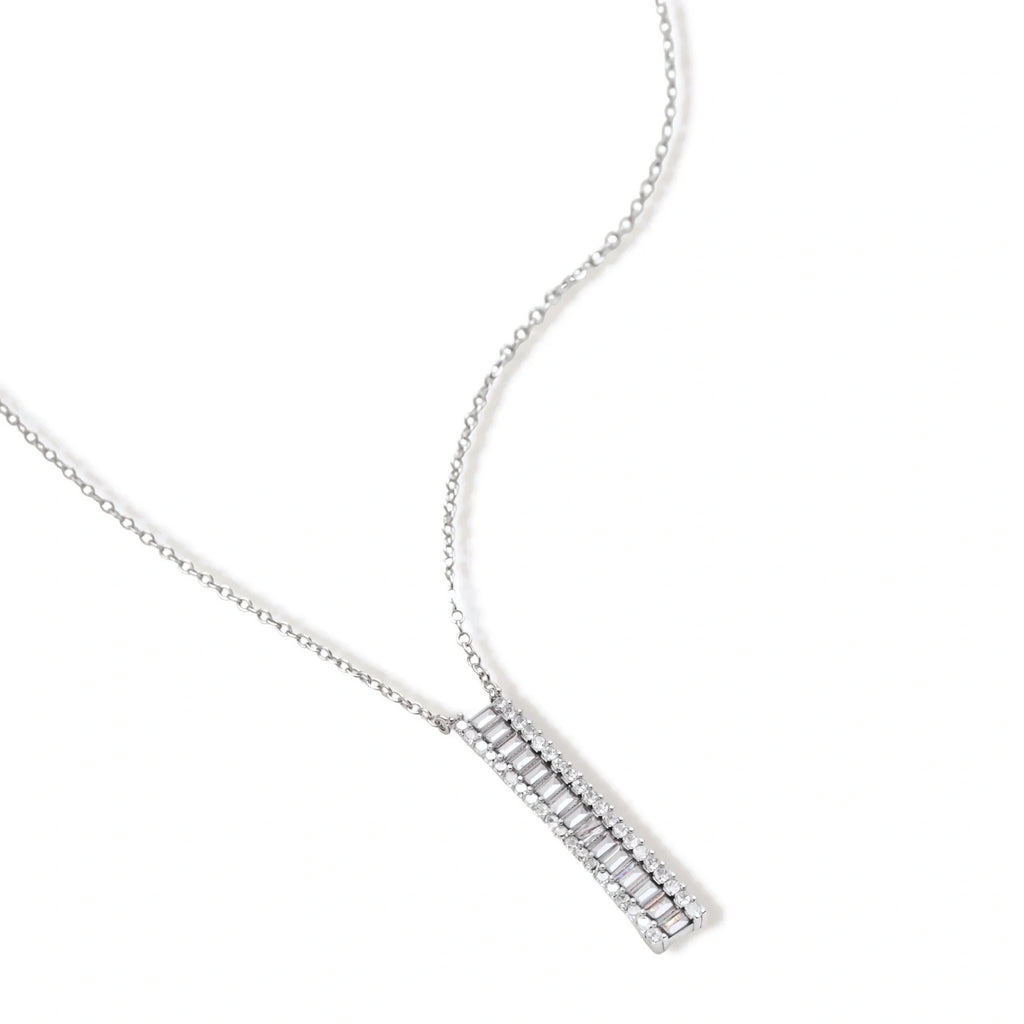 White gold plated necklace with vertical cubic zirconia pendant and matching hoop earrings on neutral background