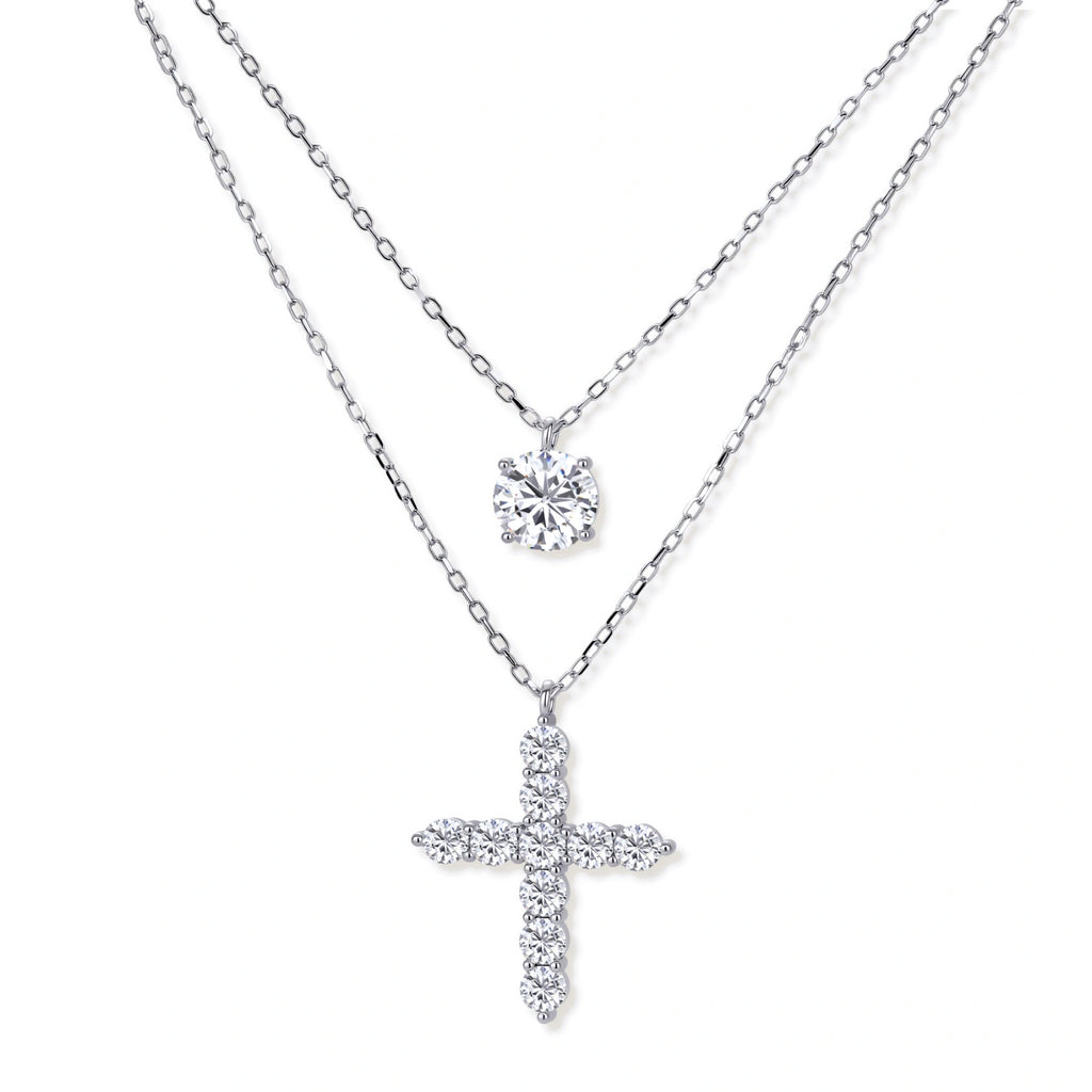 Two delicate sterling silver necklaces with moissanite stones - one solitaire pendant and one cross pendant on white background.