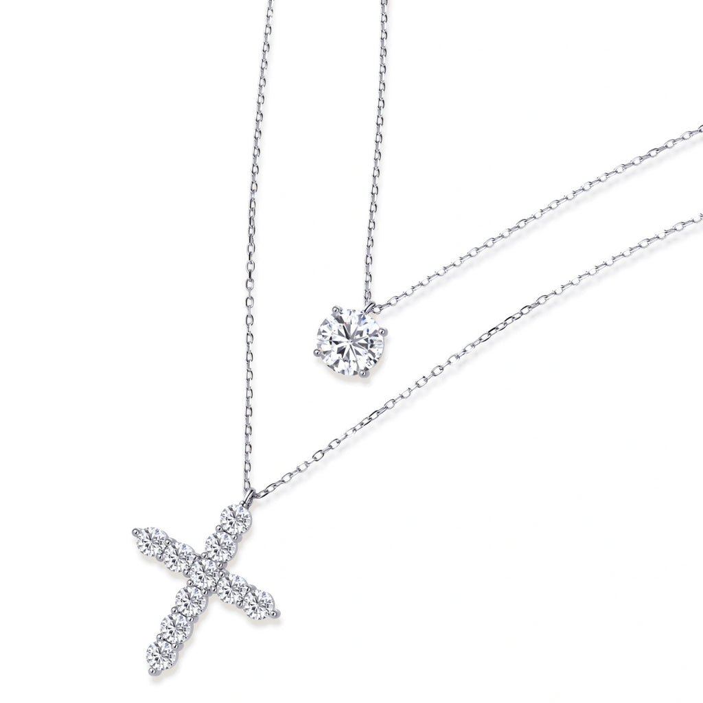 Two delicate sterling silver necklaces with moissanite stones - one solitaire pendant and one cross pendant on white background.