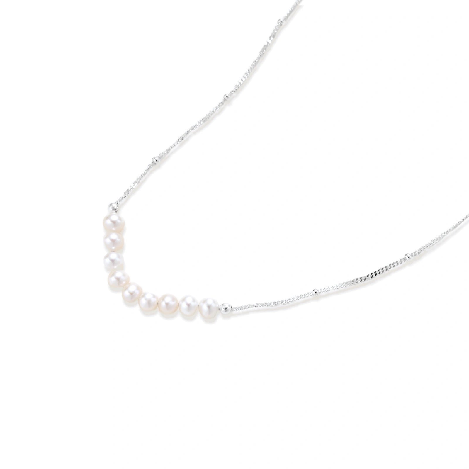 Delicate sterling silver chain necklace with small freshwater pearls arranged in a curved smile arc on cream background.