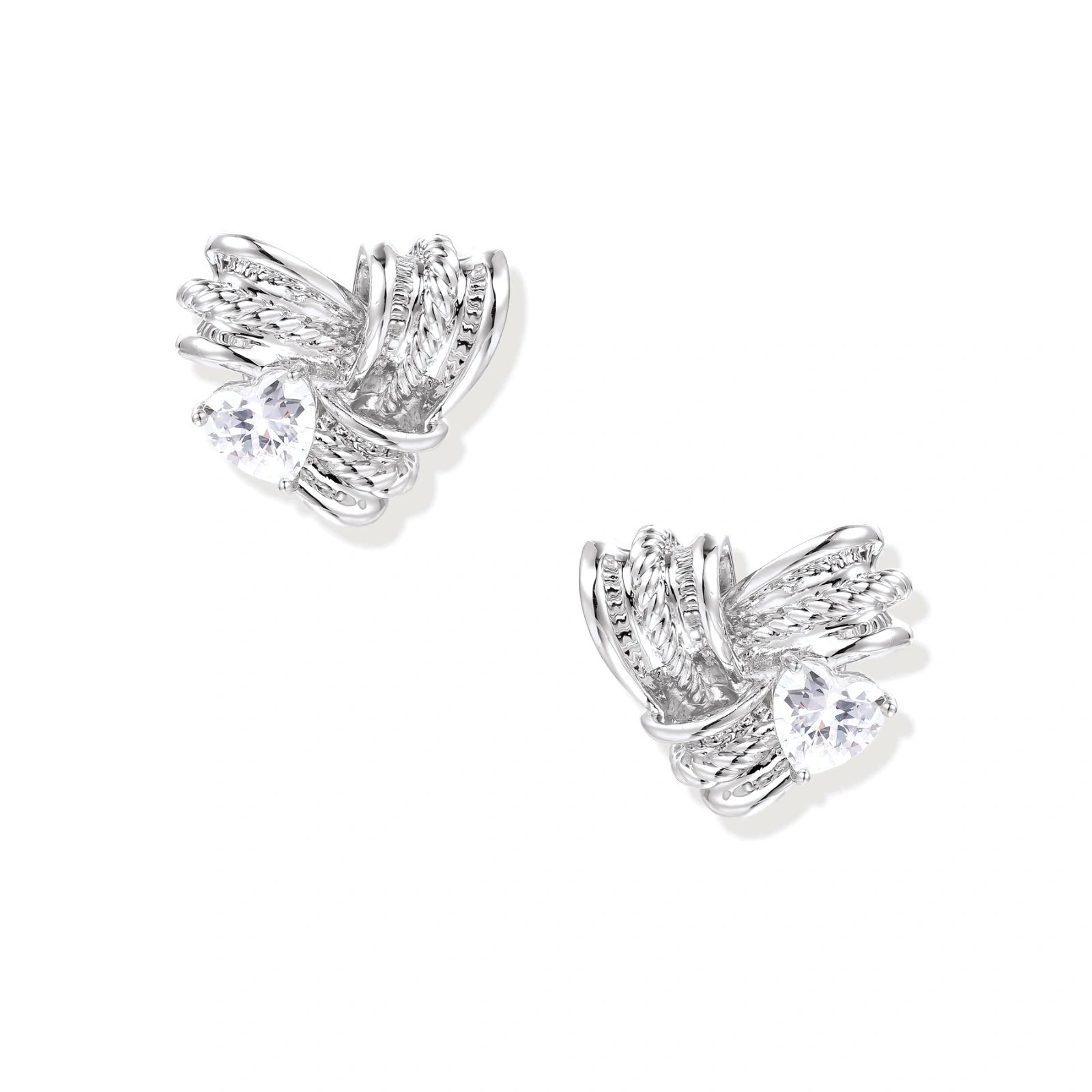 Pair of sculptural white gold-plated stud earrings with twisted ribbon design and sparkling zirconia stones on cream background