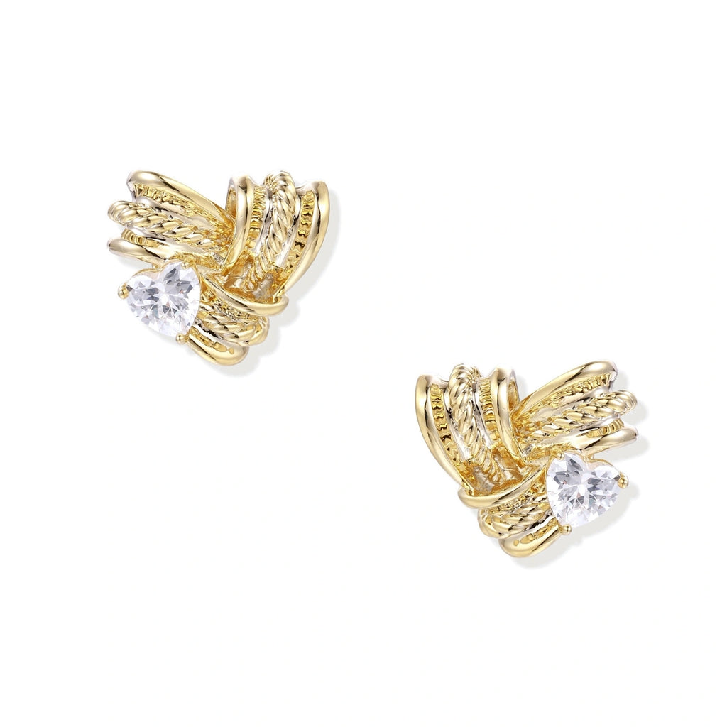 Pair of sculptural gold-plated wing stud earrings with zirconia stones on cream background, showing dimensional feather design