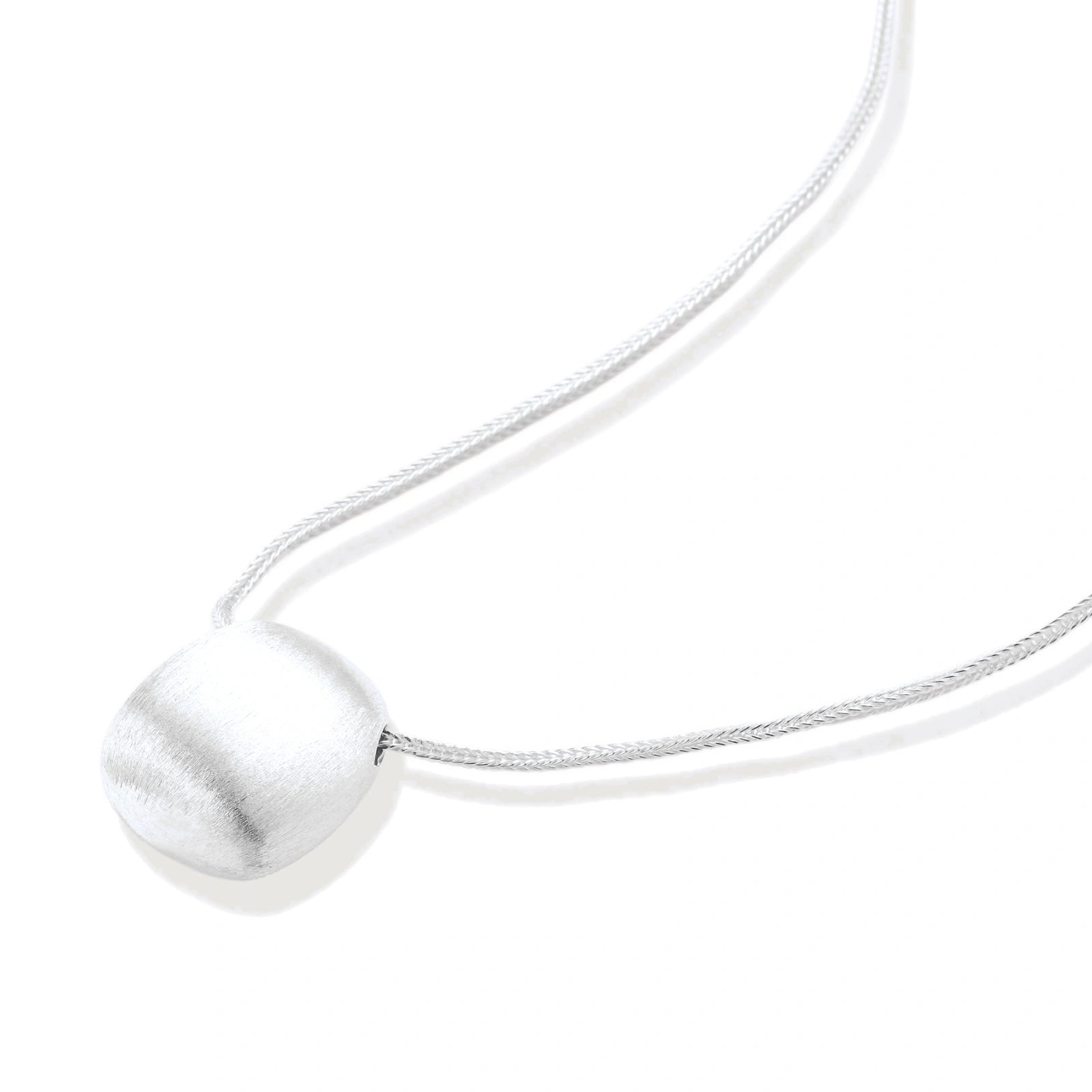 Minimalist brushed sterling silver dome pendant on delicate chain against cream background, showing matte textured finish
