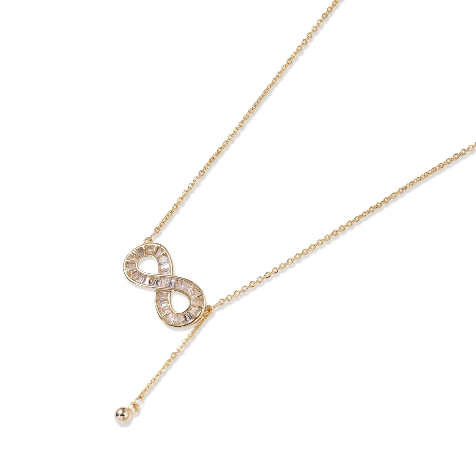 Gold infinity pendant with baguette crystals on adjustable chain against cream background.