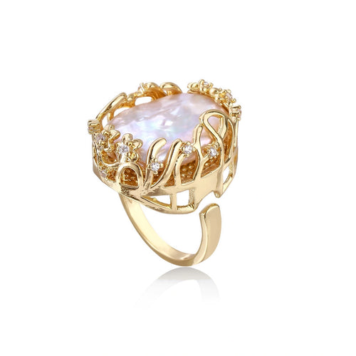 Gold filigree crown ring cradling an iridescent baroque freshwater pearl with crystal accents on white background