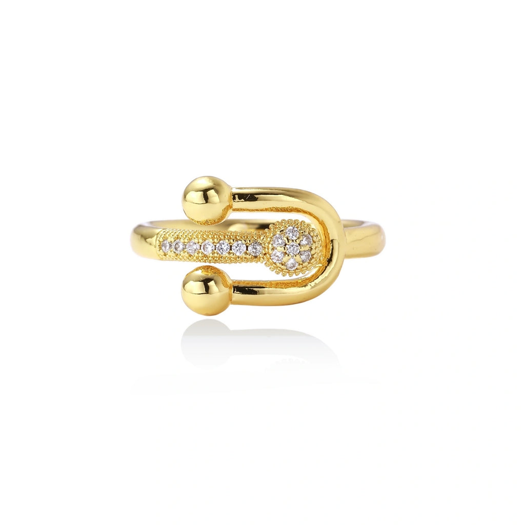 Gold-plated brass ring with safety pin design featuring pavé cubic zirconia stones and dual sphere ends