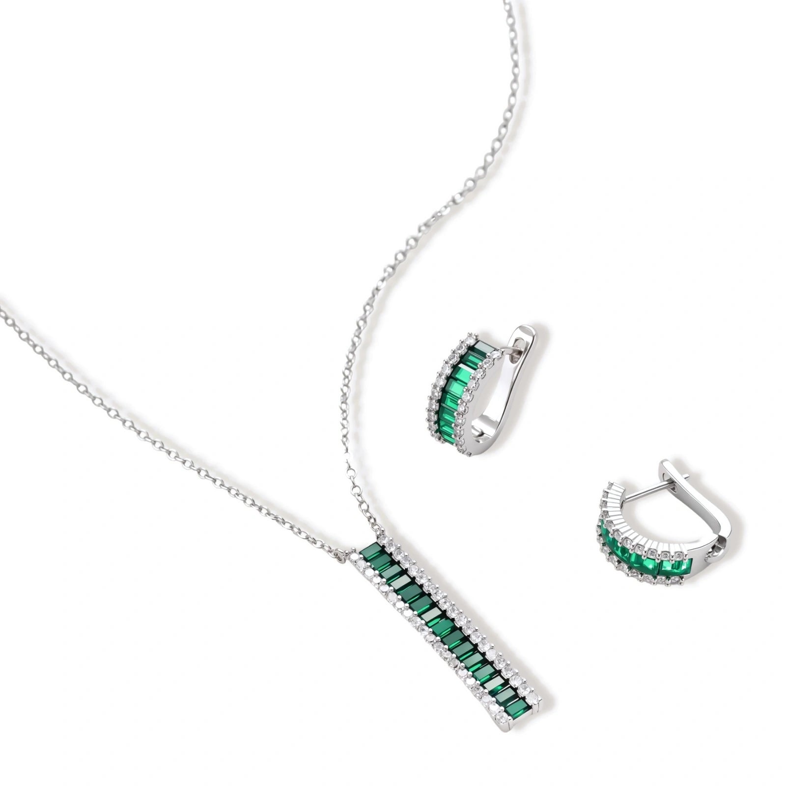 White gold plated jewelry set with emerald green rectangular stones and clear crystals in geometric rows on white background.